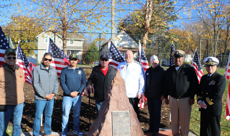 Veterans posing in from of memorial with Veterans from our community.